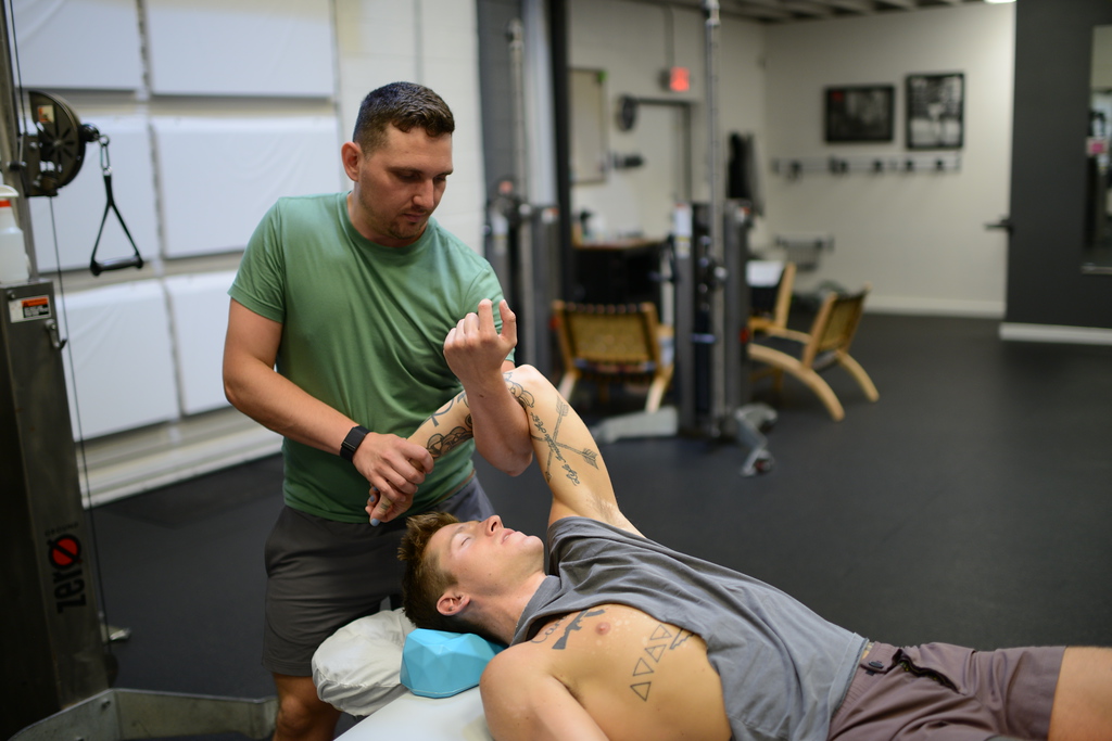 Chris supports Carter’s raised arm as Carter rests on the treatment table.